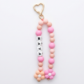 Pink and gold keychain with beads and a heart-shaped keyring on a white background